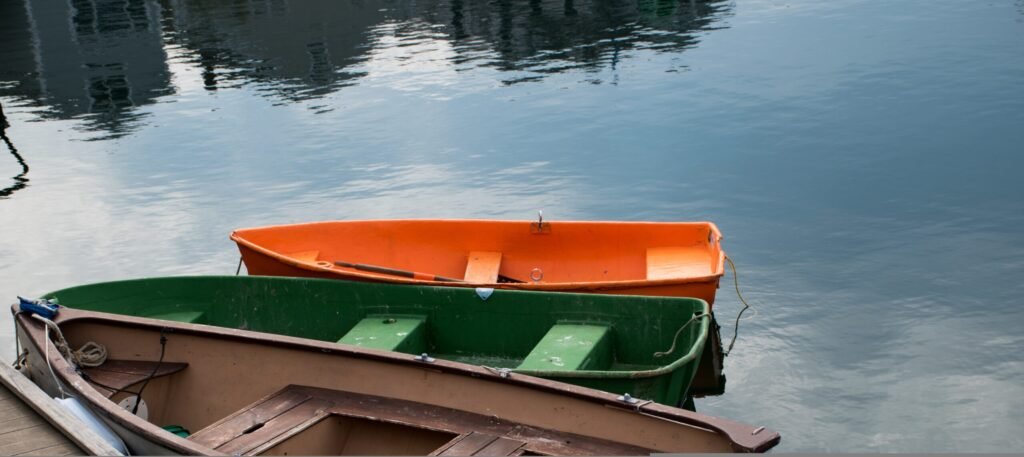 beautiful scene of four colorful boats in next to the wooden shore of the lake