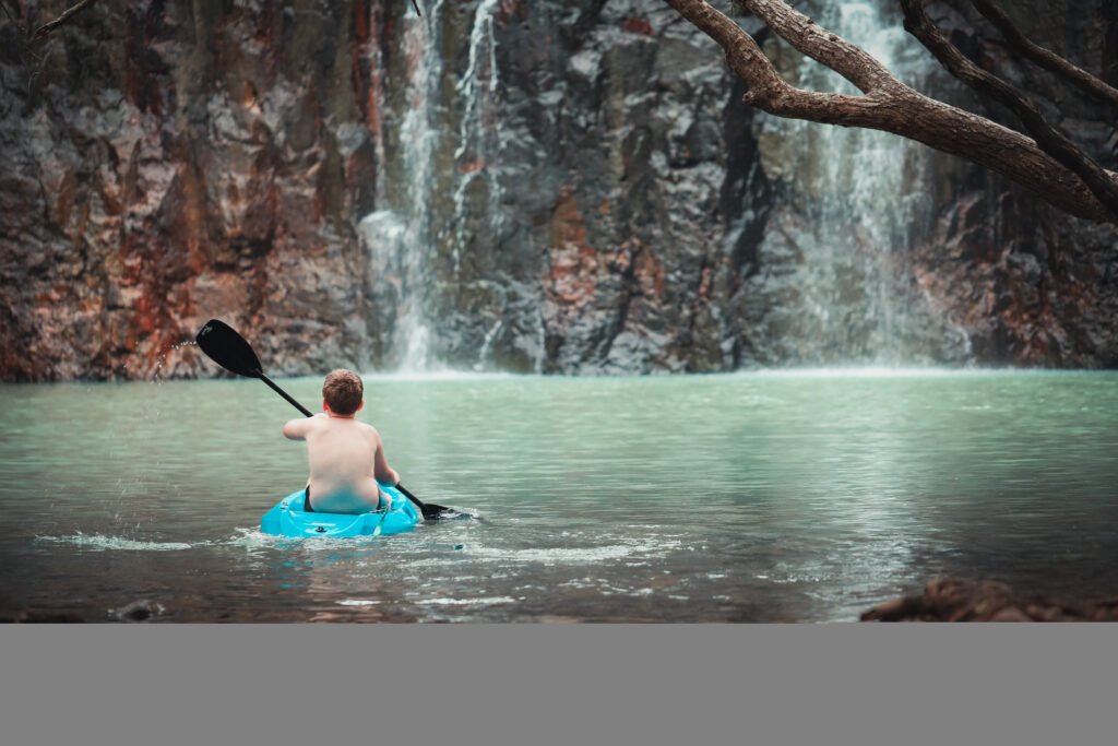 beautiful shot of a young boy kayaking at a lake