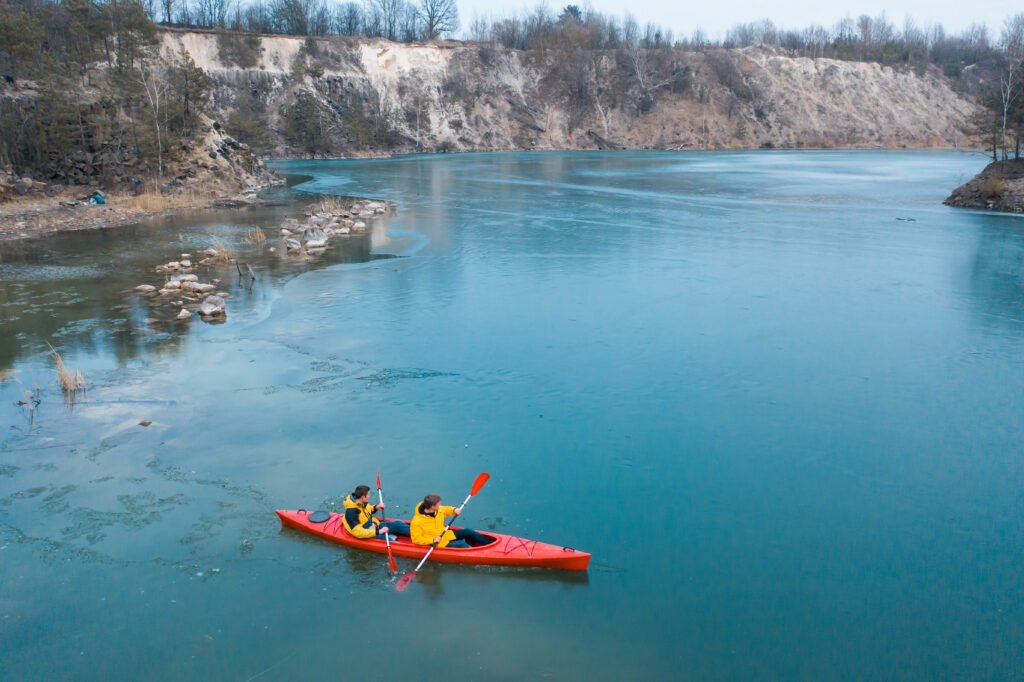 two athletic man floats on a red boat in river